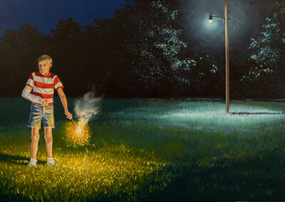 A young boy with a cast on his arm holds a sparkler in a grassy field at night. A streetlamp illuminates the scene.