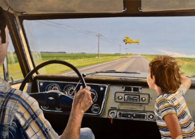 A man drives a vintage car down a rural road while a child looks out the window at a yellow crop duster airplane flying low over fields under a clear sky.